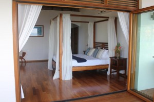 Teak four post bed with polished wooden floors