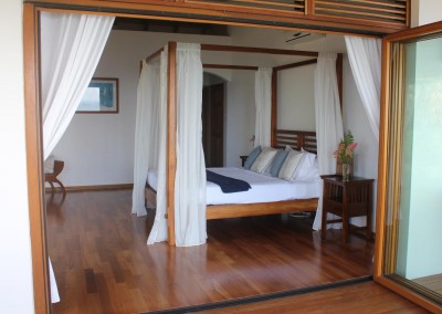 Teak four post bed with polished wooden floors